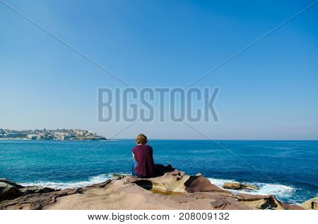 Young woman seen from behind oceanfront of bondi beach SydneyAustralia.