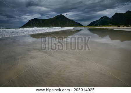 Gloomy seascape with mountains waves and reflection