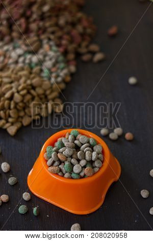 Dry cat or dog food in a orange bowl