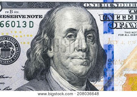 Close up of Benjamin Franklin face on 100 US dollar bill. US one hundred dollar bill closeup. Heap of one hundred dollar bills on money background.