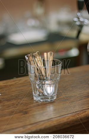 Tea spoons in transparent glass on a wooden bar