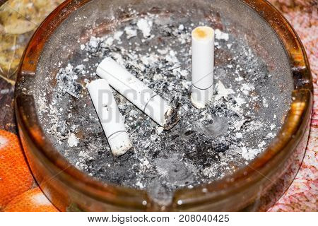 Three cigarette butts in the dark ashtray