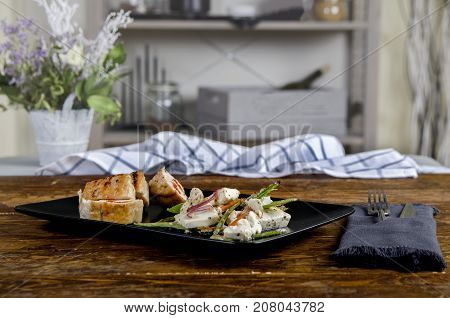 Stuffed turkey breast on the black plate snd wooden background. Chicken roulade - Stock image