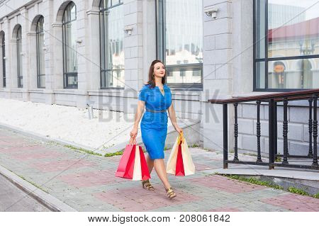 After day shopping. Close-up of young woman carrying shopping bags while walking along the street