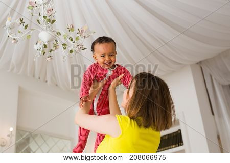 happy family. Mother throws up baby, playing at home.