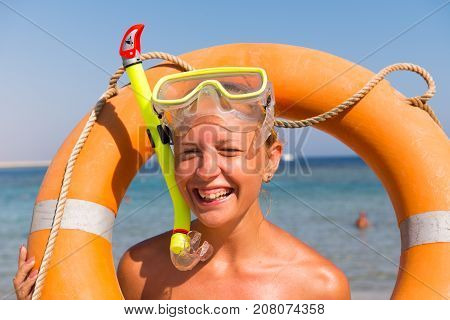 Cheerful young tan woman wearing snorkeling mask at the beach with lifesaver buoy