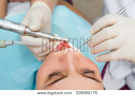 Hands of dentist curing a female patient with drill, closeup. slective focus.