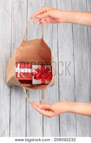 Hands of a young girl open a paper bag full of gifts. Close-up. Christmas concept.