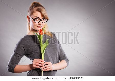 Delicacy and subtlety of women. Young adorable woman with spring flower. Portrait of beauty delicate girl in glasses with red beautiful tulip.