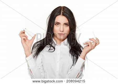 Portrait of angry and sadly brunette woman looking at camera, with arms up with two  bootless of nasal spray. Permanent method for flu and illness. Medicament for allergy.