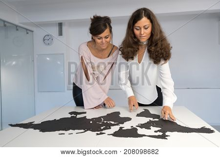 Twins girls fixing the world map on the table
