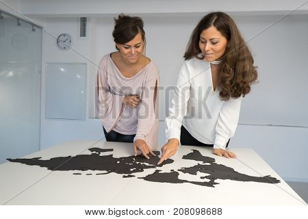 Twins girls fixing the world map on the table