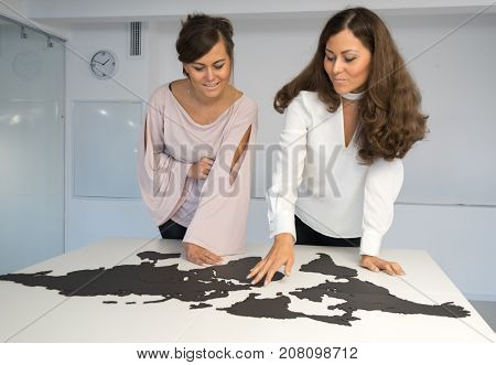 Twins girls fixing the world map on the table