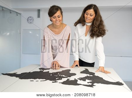 Twins girls fixing the world map on the table