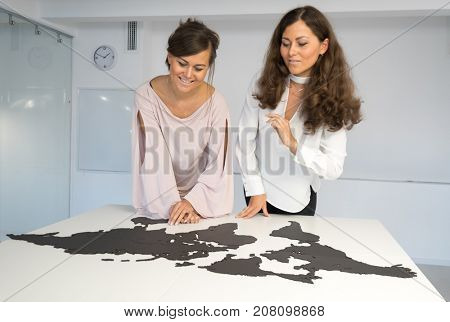 Twins girls fixing the world map on the table