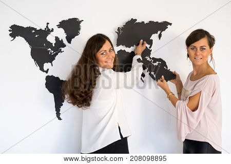 Girls twins fixing the world map on the wall