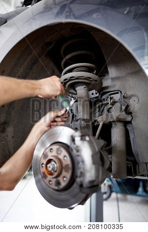 An unidentified mechanic repairing brake pads using tools from a green box