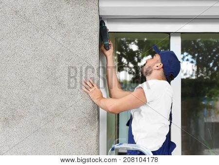 Man installing roller shutter on window