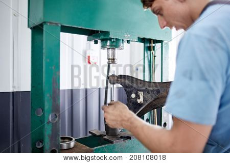 The mechanic sharpens the part on the machine for further installation on the car