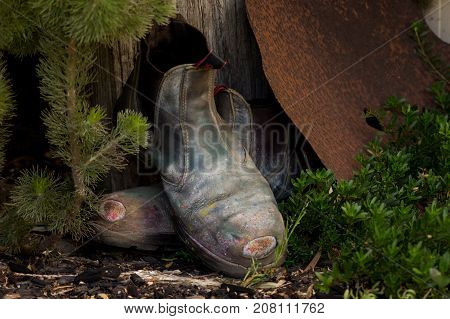Old pair of work boots left by wooden fence post