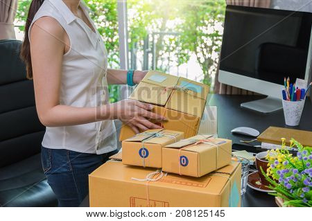 Closeup hand Young asian teenager owner business woman tying a rope prepaing package the product with office equipment online shopping entrepreneur and alpha generation life style concept