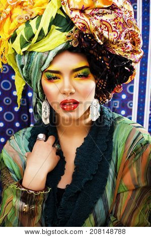 beauty bright woman with creative bright make up, many shawls on head like cubian, ethno look closeup