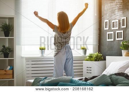 young happy woman woke up in the morning in the bedroom by the window with her back