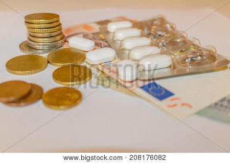 White Tabletts With Euros Banknotes And Coins. Concept Pharmaceutical Business, Cost Of Health, Mede