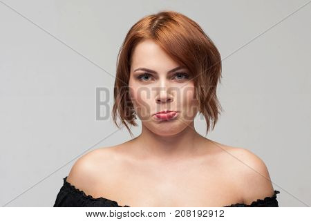 Unpleasant behavior. Female taking offence. Upset young girl portrait on grey background with free space. Capricious attitude, sadness, complaints concept