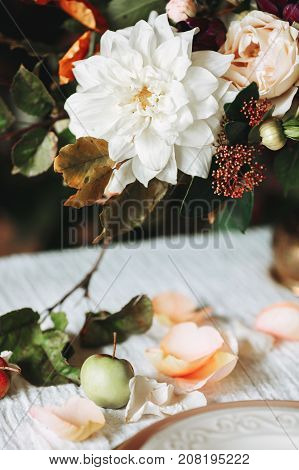 Still life with autumn flowers with leafs on white table with plate