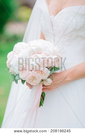Wedding bouquet in rose and white tones in hands of the bride
