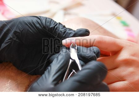 Nail Salon. Closeup Of Female Hand With Healthy Natural Nails Getting Nail Care Procedure. Closeup Hands Removing Cuticles With Professional Nail Tool, Metal Clippers. Beauty Manicure.