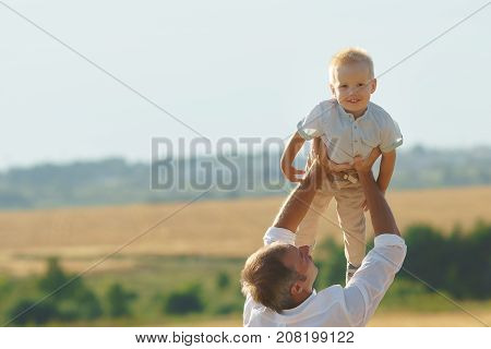 Father playing with son on summer weadow. Family walking with child outdoor copyspace