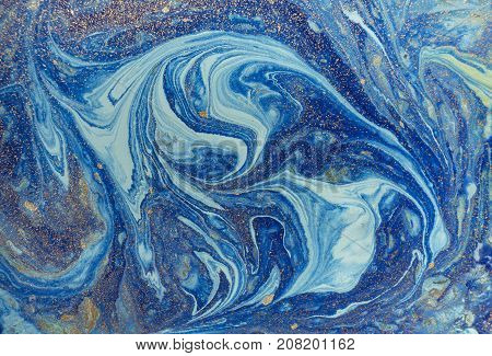 Marbled blue abstract background with golden sequins. Liquid marble ink pattern