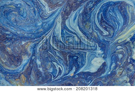 Marbled blue abstract background with golden sequins. Liquid marble ink pattern