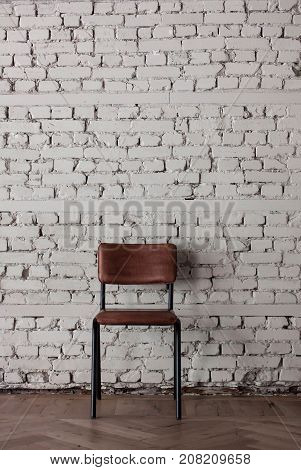 Empty modern chair near white brik wall in minimalistic and loft style