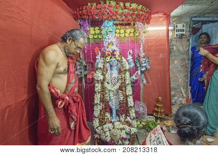 KOLKATA INDIA - JUNE 17 2017 - Hindu priest worshipping Goddess Kali at night during Kali Puja Hindu festival of Deepavali or Diwali. Celebtated all over India. Shot under mixed light.