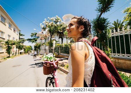 Smiling eastern girl on vintage bicycle with backet of flowers