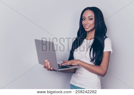 Portrait Of Successful Afro Lady With Laptop, Typing On A Keyboard, Standing On Pure Gray Backgrund,