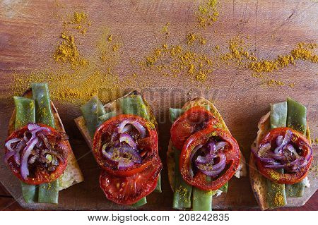 Summer sandwich prepared with fried red onion, tomato and kidney beans on the old chalkboard. Top view