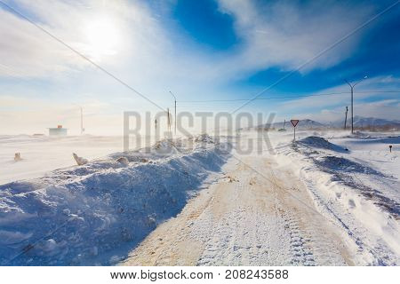 Dangerous snowing road with road signs for driving cars and public transport during blizzard or snowstorm with poor visibility on the road in rural.