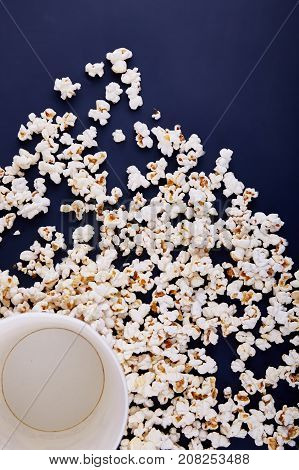 An empty bowl of popcorn, all popcorn scattered on a blue background, sell it to the cinema