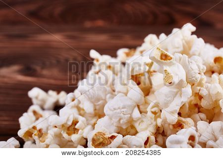 Spilled on the edges of popcorn on a wooden brown background which is sold in the cinema