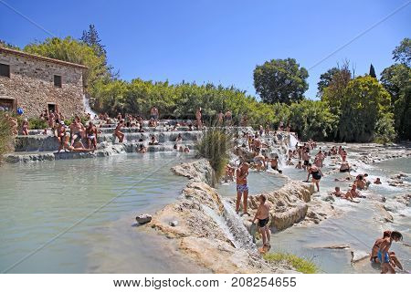 SATURNIA, ITALY - JULY 26, 2017: Tourists swimming and relaxing in hot springs at Cascate del Mulino in Saturnia, Grosseto, Tuscany, Italy. This world famous natural spa has natural waterfalls and hot springs.