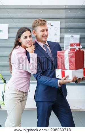 Young happy employees are standing with gifts in the office. Close-up. In full growth.
