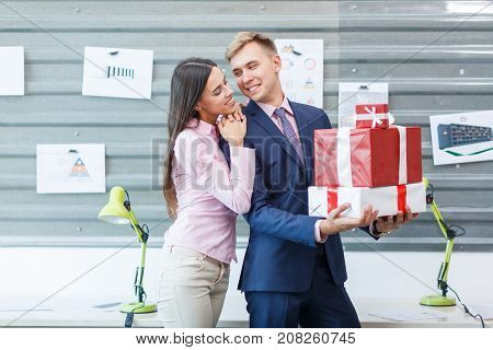 Young happy employees are standing with gifts in the office. Close-up.