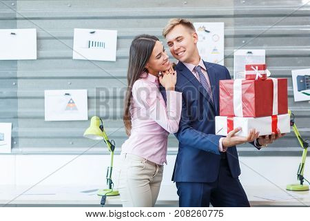 Young happy employees are standing with gifts in the office. Close-up.