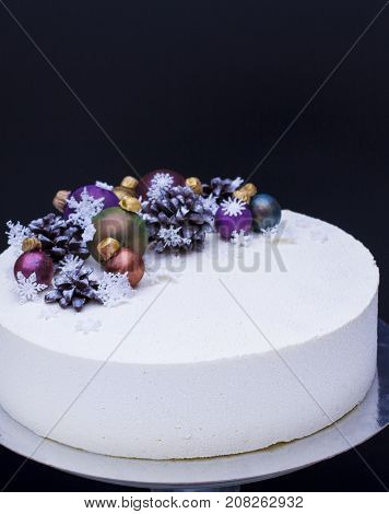 A cake for a Christmas holiday or a new year. A cake with chocolate cones and Christmas-tree toys is made of chocolate. Cake on snow background