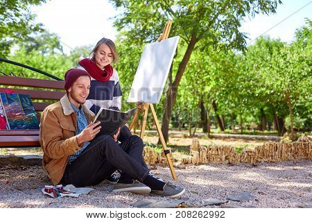 A set of artist with paints, brushes and author's pictures on a bench