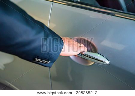 Male hand holding silver doorhandle a white car